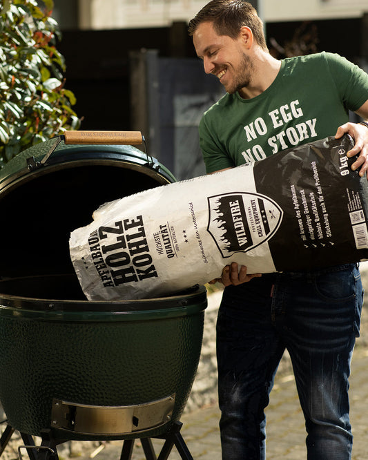 Mann füllt Wildfire Apfelbaum Holzkohle in ein Big Green Egg Keramikgrill, natürliche Grillkohle mit Apfelaroma für einzigartigen Geschmack.